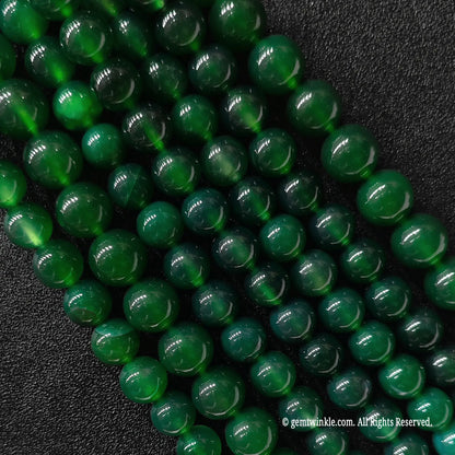Multiple strands of green agate round beads held in hand for scale and size range verification