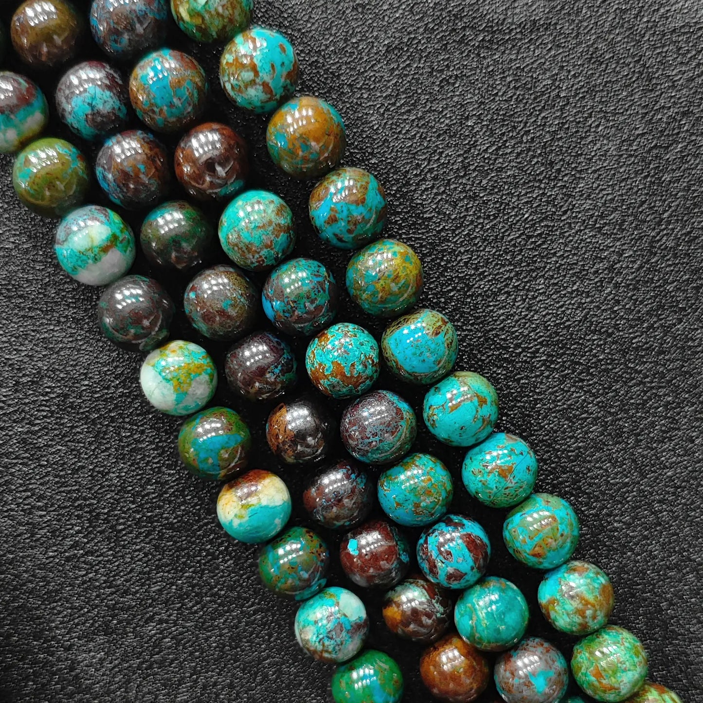 Macro closeup of green chrysocolla phoenix stone smooth round beads showing vibrant matrix pattern