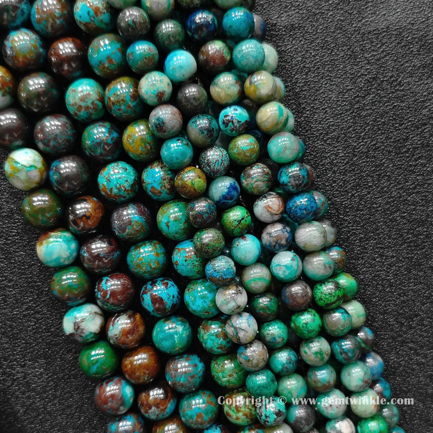 Perspective view of green chrysocolla round beads displaying rich polished surface across various sizes