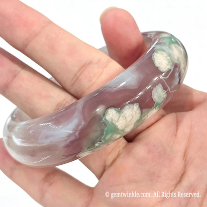 Full green cherry blossom agate bangle resting on open fingers displaying natural floral plume distribution