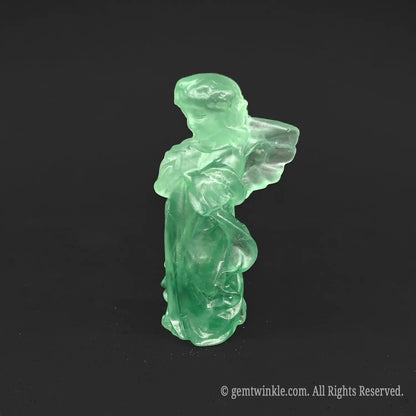 Side view of a natural green fluorite guardian angel crystal statue showing elegant carved wing profiles and translucent minty colors
