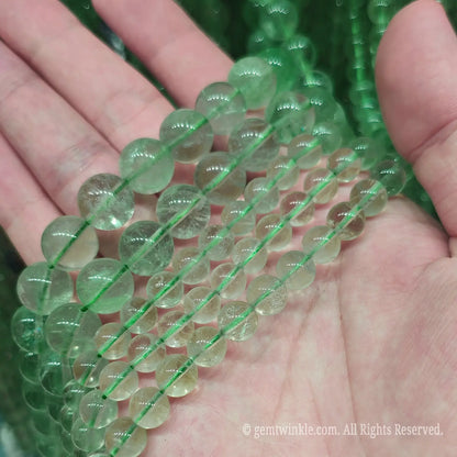 Size comparison of natural green fluorite crystal round beads from 4mm to 14mm held in hand for boutique jewelry creators
