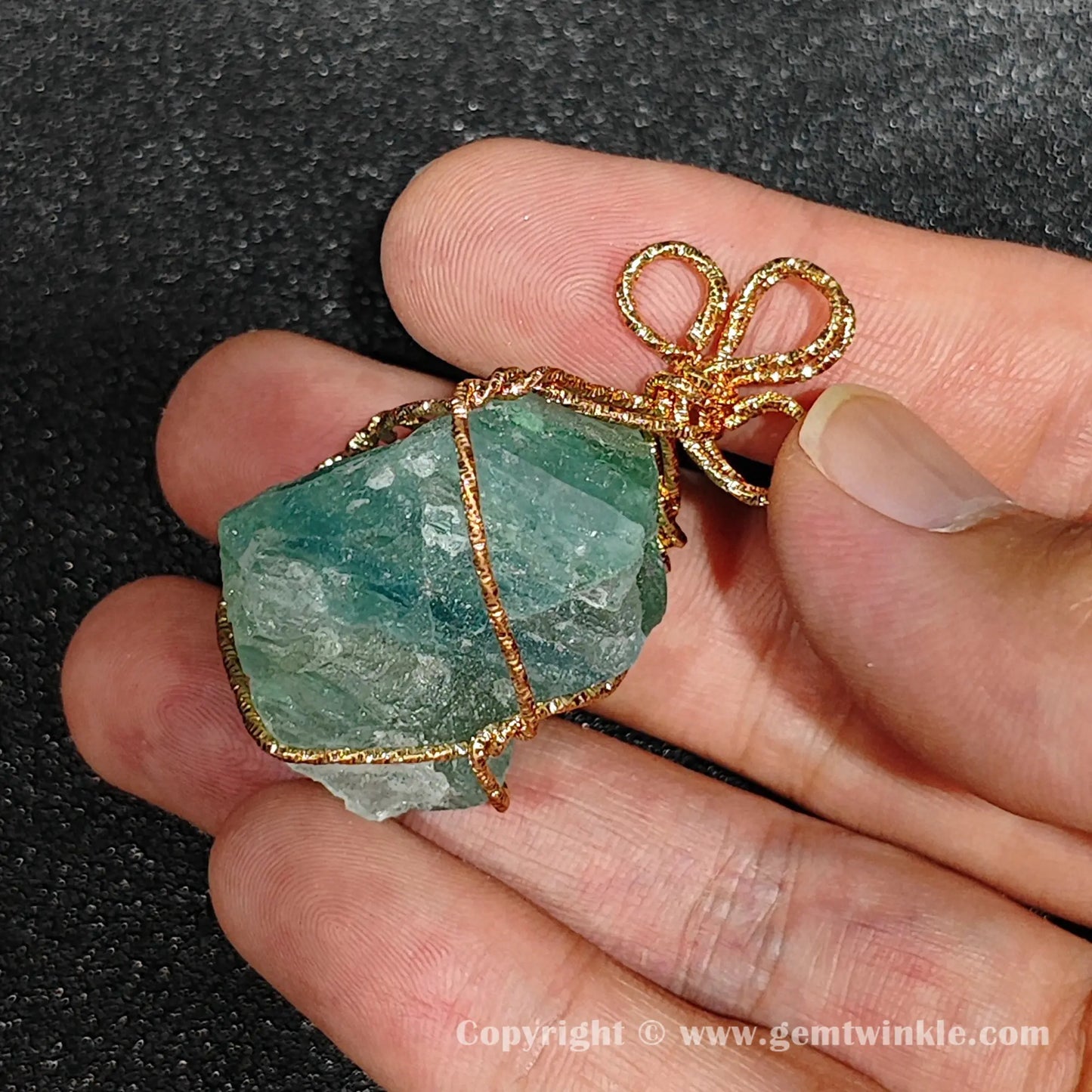 Reverse handheld view showing natural cleavage fractures on 3cm green fluorite rough wire wrapped pendant