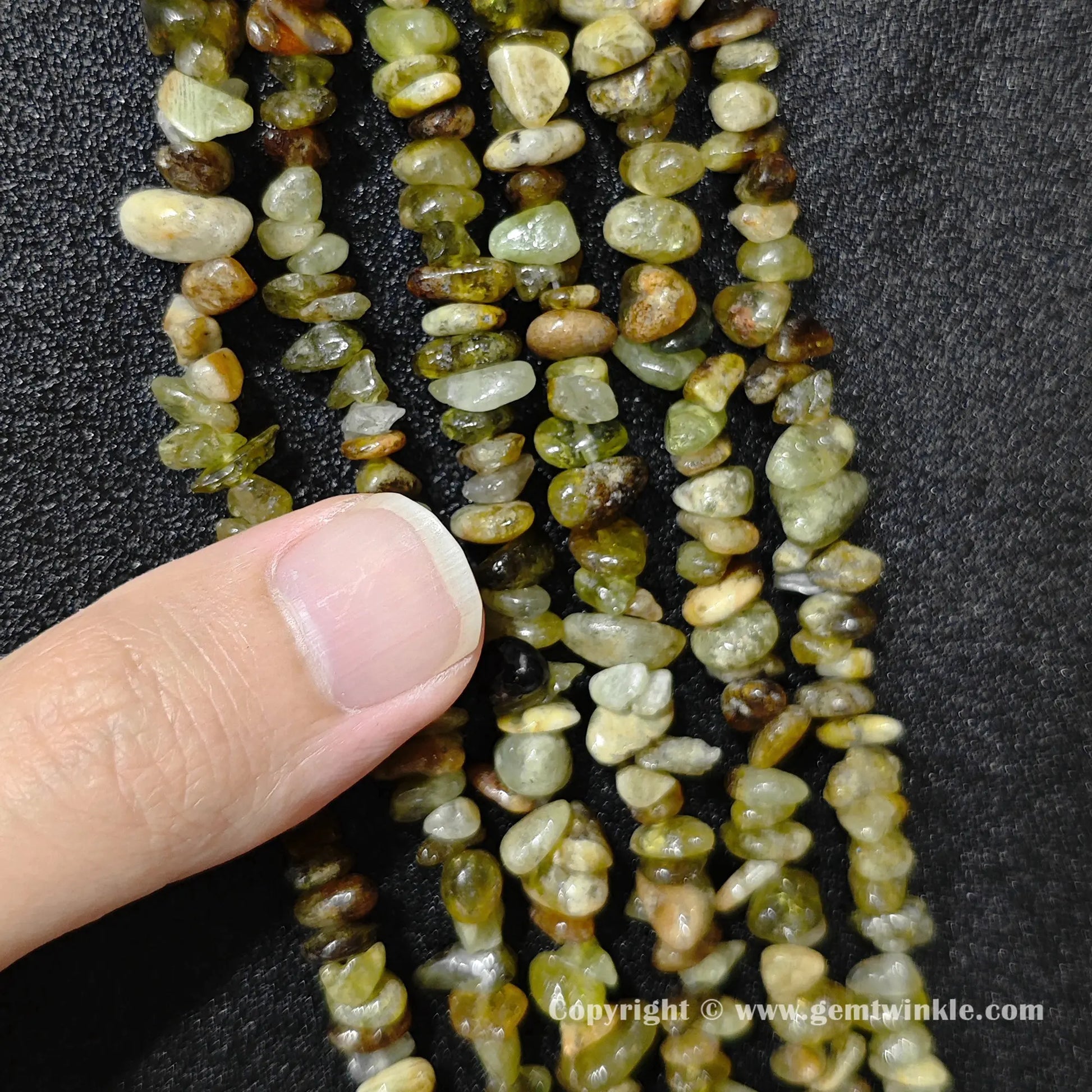 Natural green garnet chip bead strand held over hand for size scale
