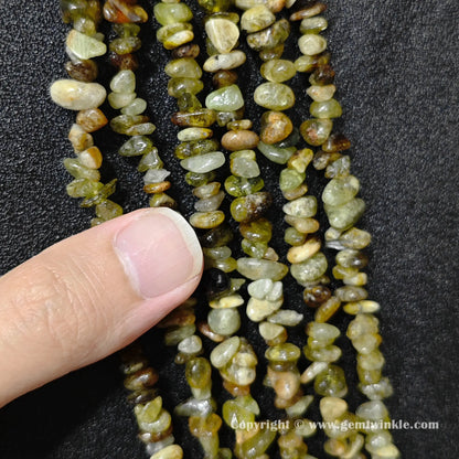 Natural green garnet chip bead strand held over hand for size scale