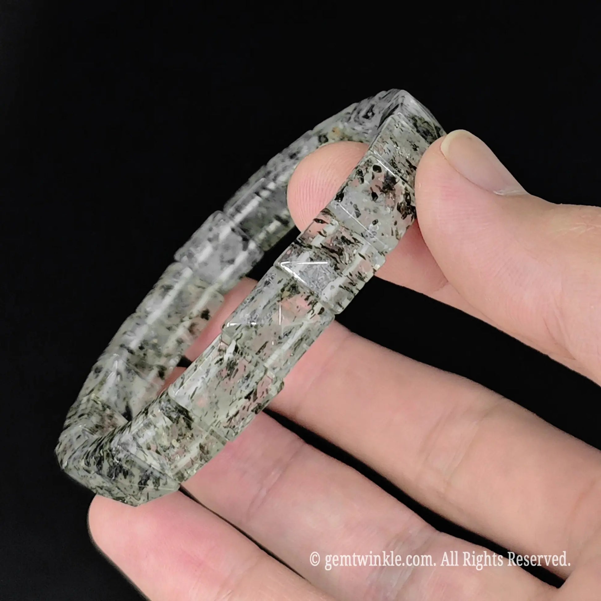 hand holding 17cm womens green mica clear quartz pyramid cut stretch bangle