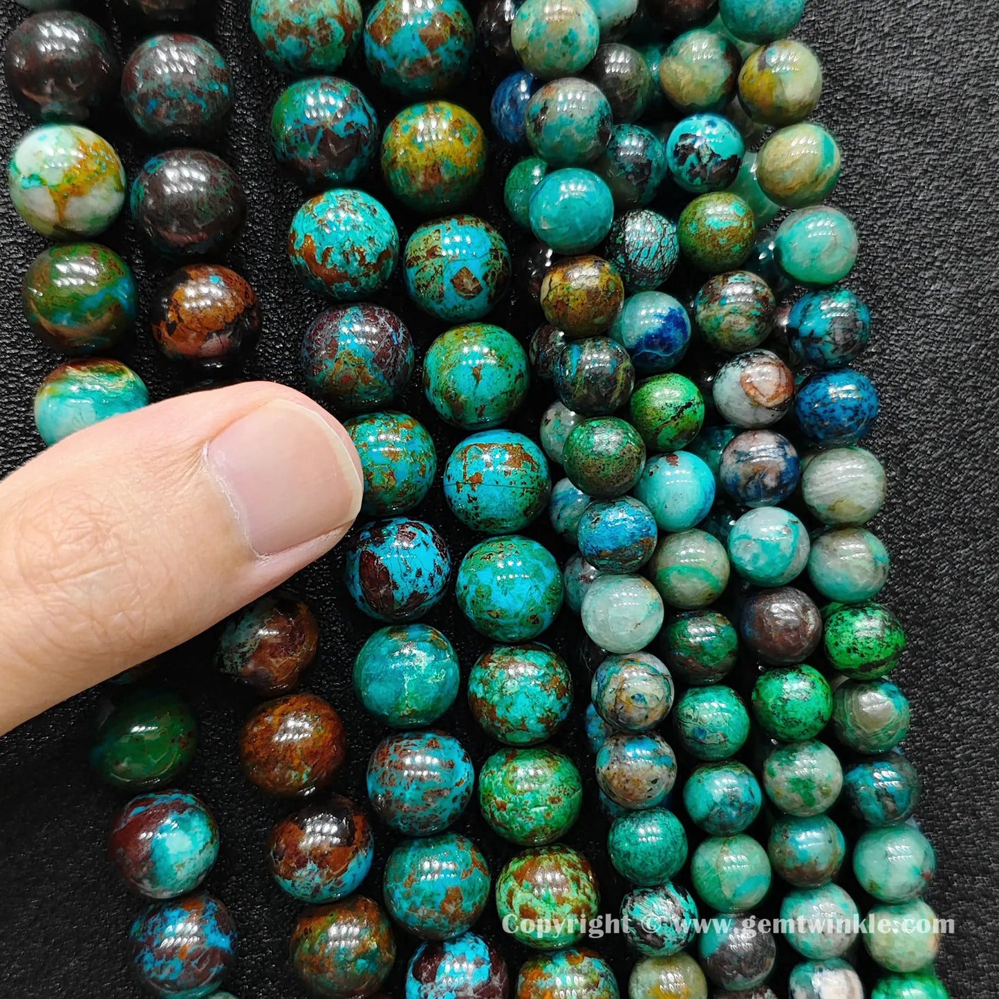 Close up view of green phoenix stone round beads inspected on fingers for quality and texture preview