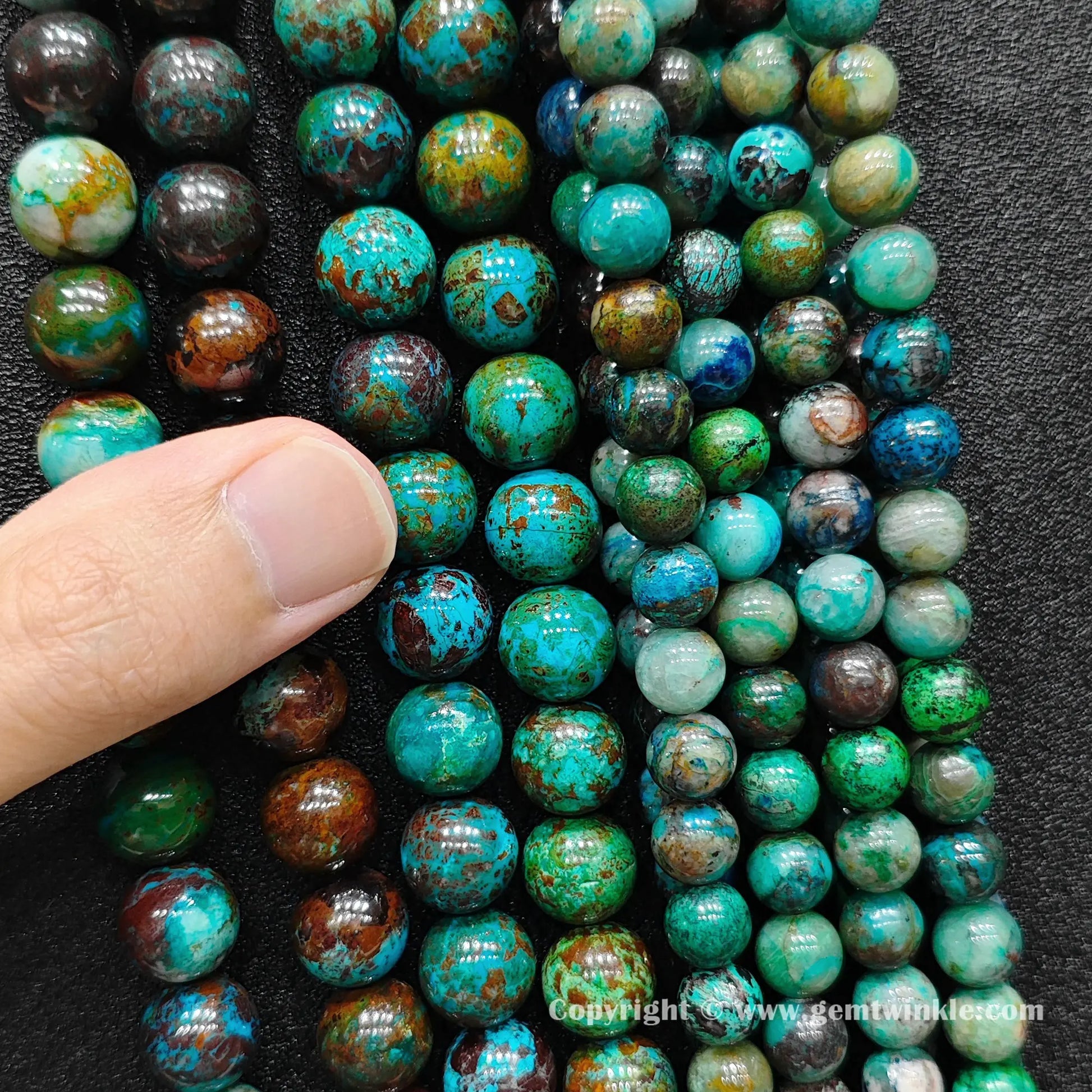 Close up view of green phoenix stone round beads inspected on fingers for quality and texture preview