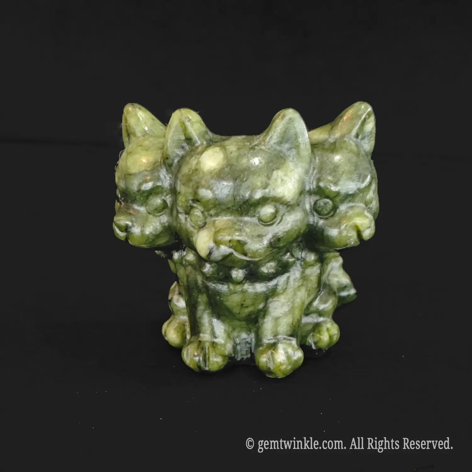 A standalone front view of a dark mottled green serpentine three headed dog figurine showcasing rustic earthy mineral textures and detailed face carvings