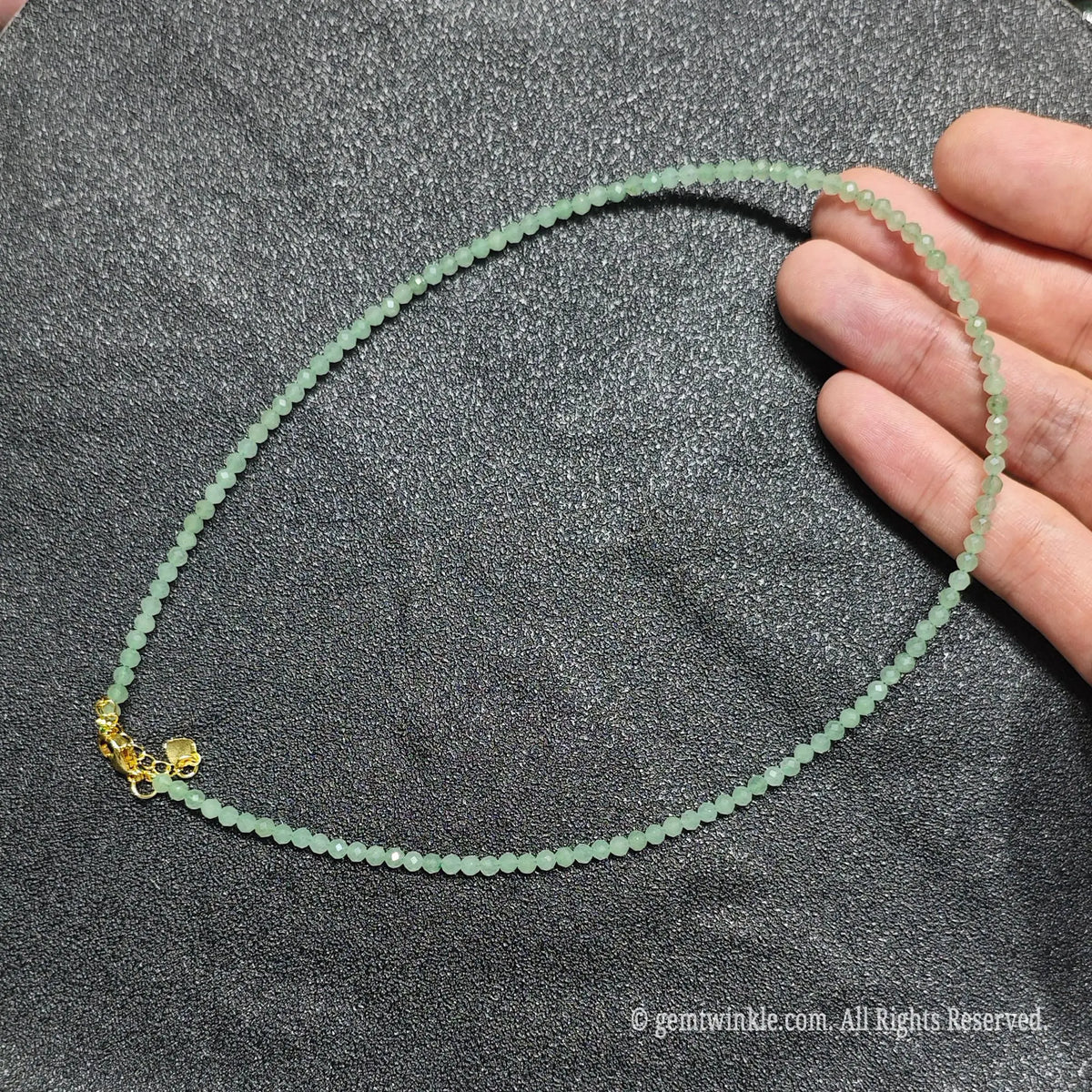 Hand holding 3mm faceted green aventurine necklace showing jade green tone and gold lobster clasp