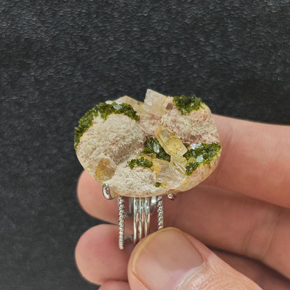 Green epidote quartz crystal cluster ring held in hand side view displaying organic mineral texture
