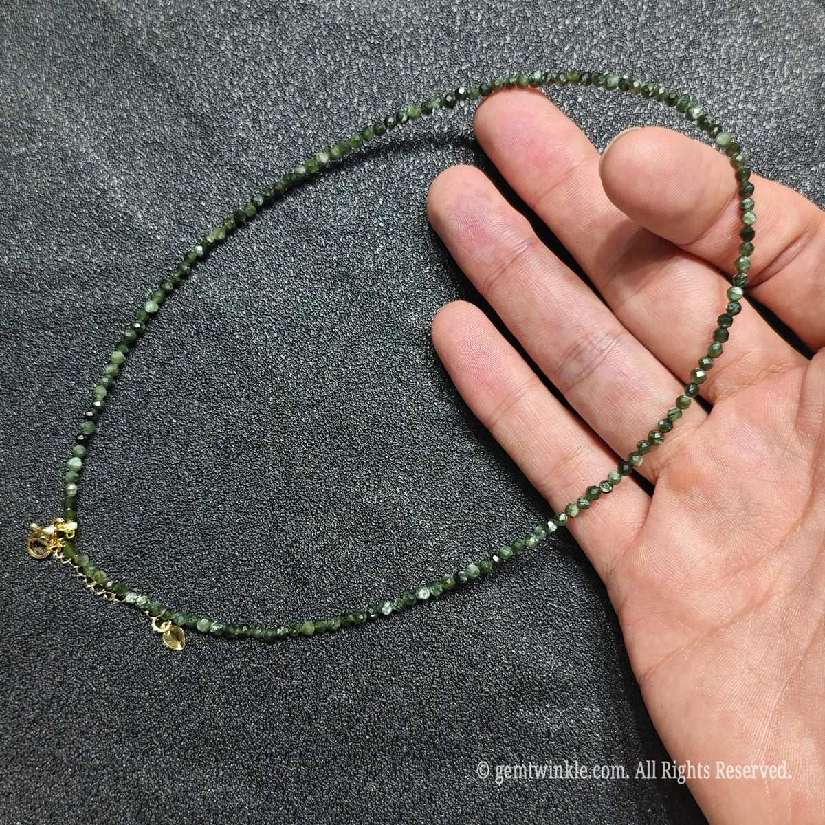 Hand holding dainty 3mm seraphinite choker showcasing deep olive green silver feather patterns