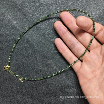 Hand holding dainty 3mm seraphinite choker showcasing deep olive green silver feather patterns