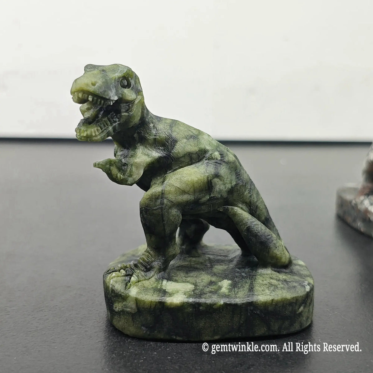 side profile view of green serpentine carved t-rex dinosaur figurine with open jaw and sturdy base