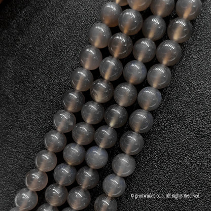 Four parallel bulk strands of polished grey chalcedony mineral loose beads arranged to check batch color consistency