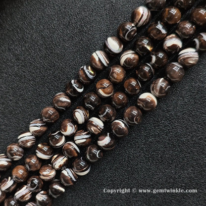 Multiple strands of grey and brown banded mother of pearl round beads on black background