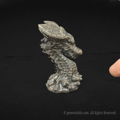 Close up of a natural grey spotted stone dragon bust sculpture held in hand showcasing thick organic rock texture