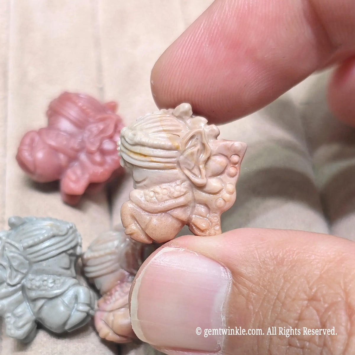 Group display of multiple miniature flower fairy stone charms resting on a soft surface in various natural colors