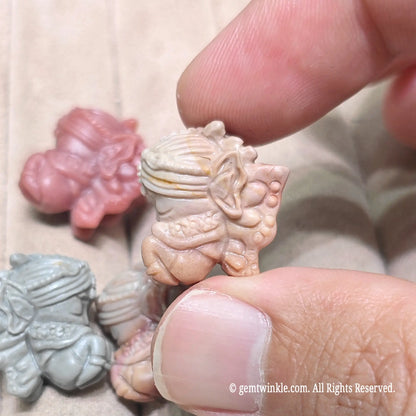 Group display of multiple miniature flower fairy stone charms resting on a soft surface in various natural colors