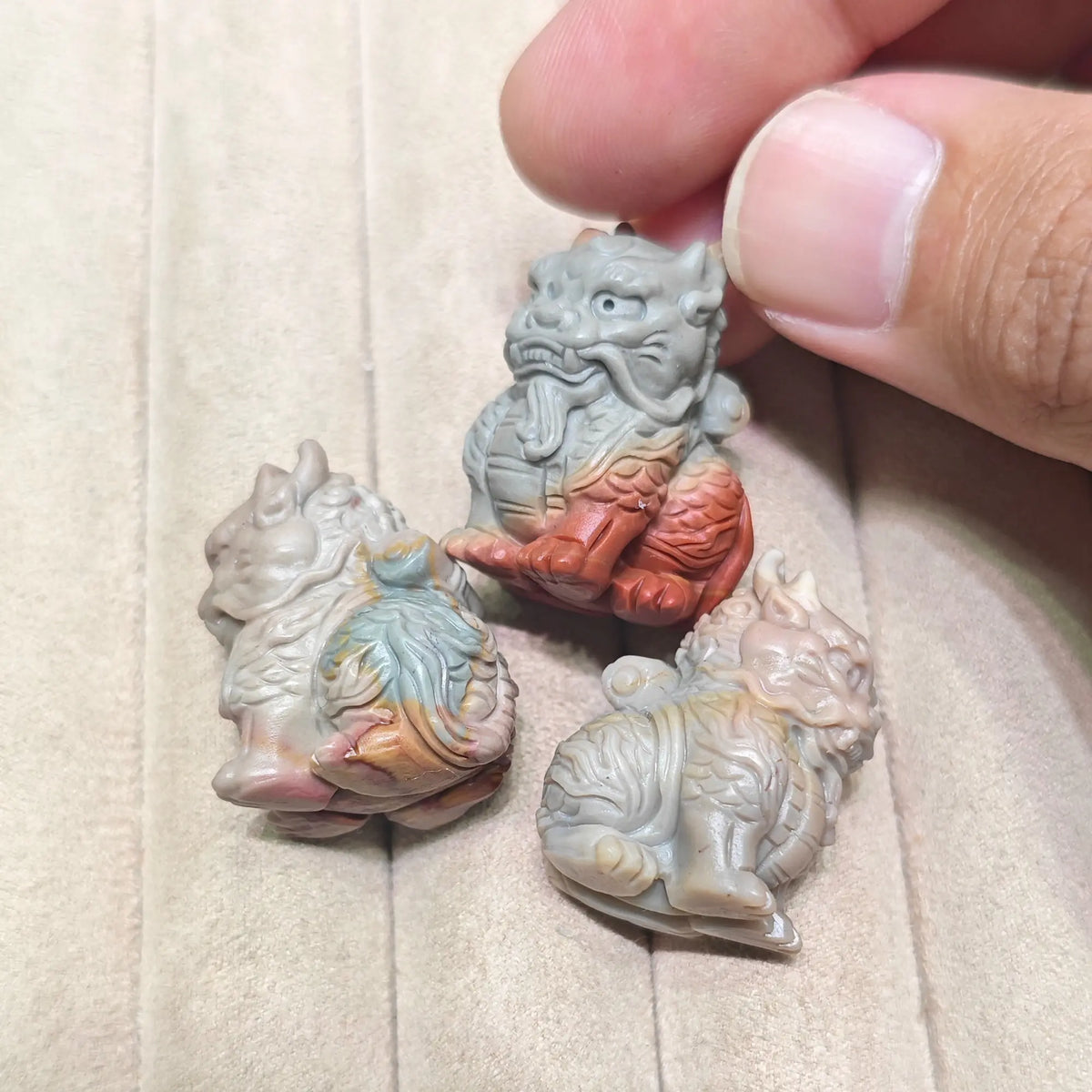 Top down group display of multiple mini Kirin statues resting on a soft surface showing color variations