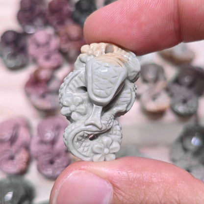Top down group display of tiny plum blossom snake stone carvings in various natural colors