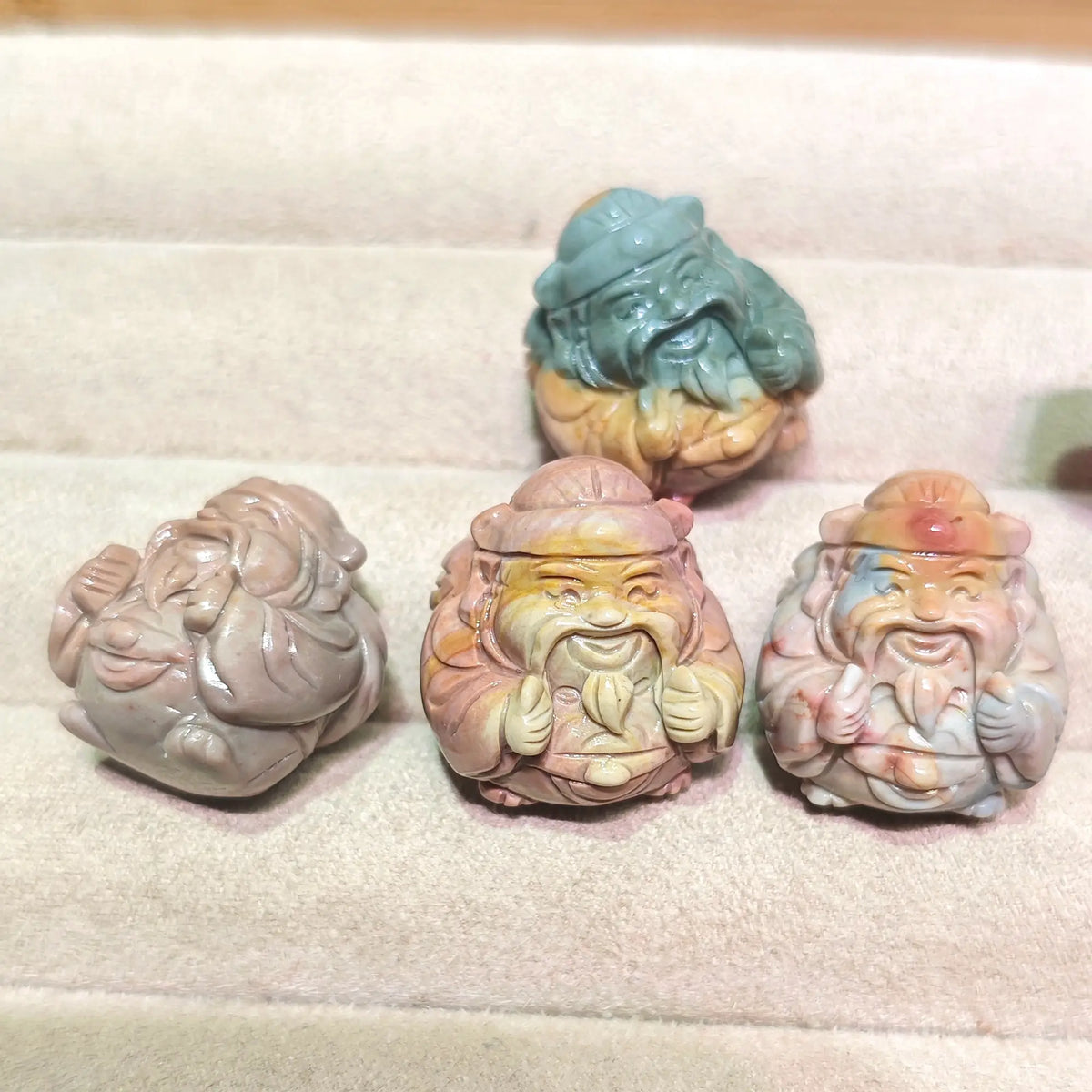 group display of five mini caishen god of wealth figurines resting on tray in various natural stone colors