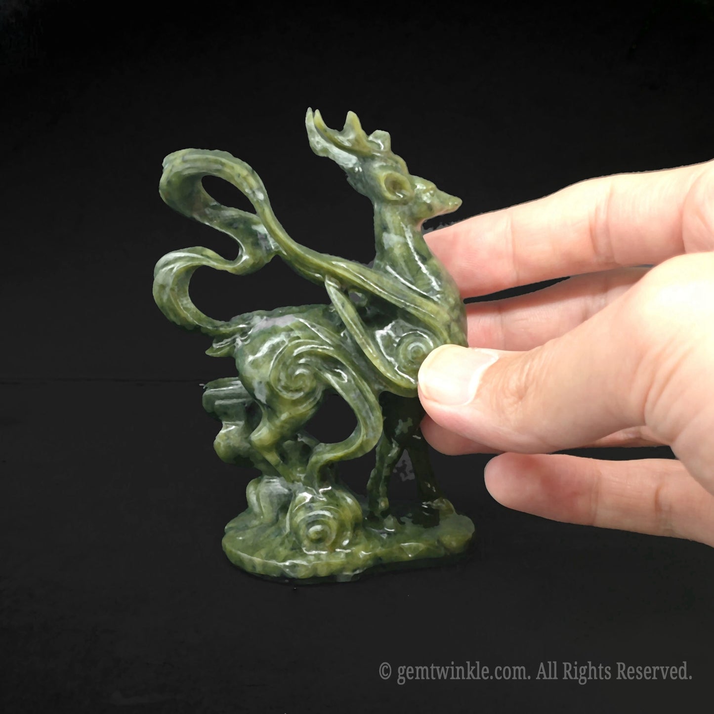 Close up view of the polished muscle and wing definition on a serpentine stone deer statue held by hand for scale