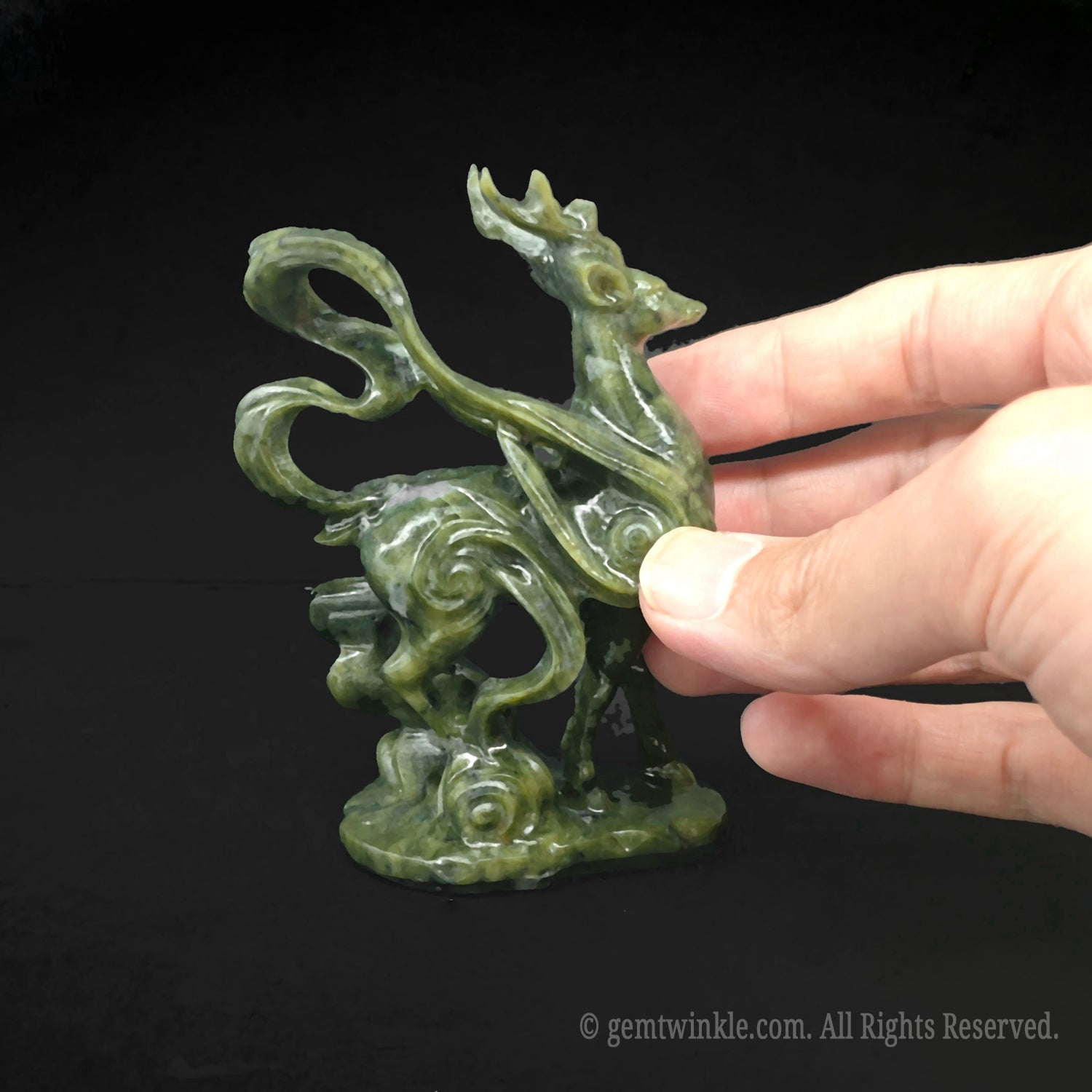 Close up view of the polished muscle and wing definition on a serpentine stone deer statue held by hand for scale