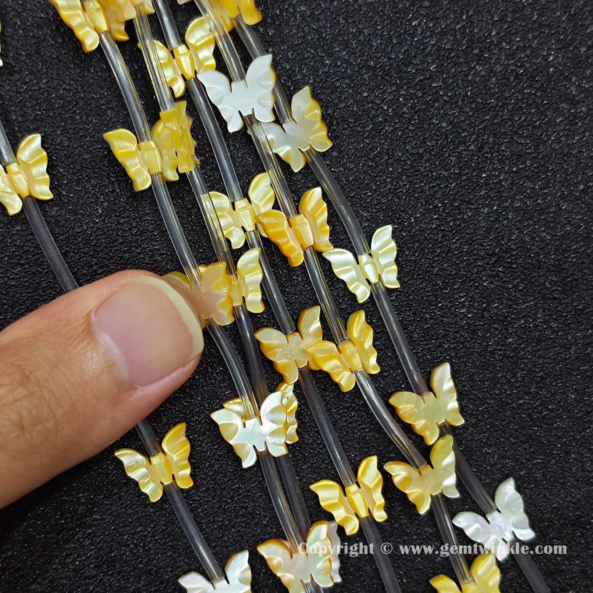 hand held scale preview of 12x10mm carved yellow shell butterfly beads