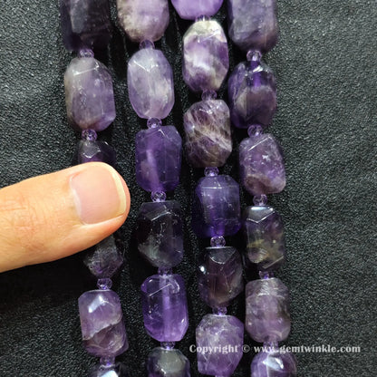 hand holding large purple amethyst faceted barrel beads showing scale and texture