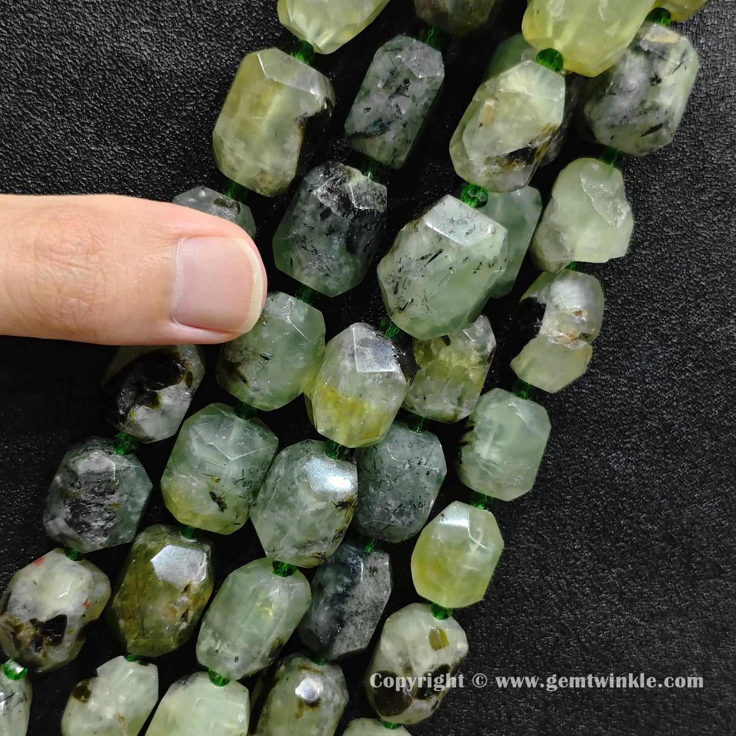 hand holding raw green prehnite faceted barrel beads showing size and texture