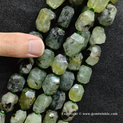 hand holding raw green prehnite faceted barrel beads showing size and texture