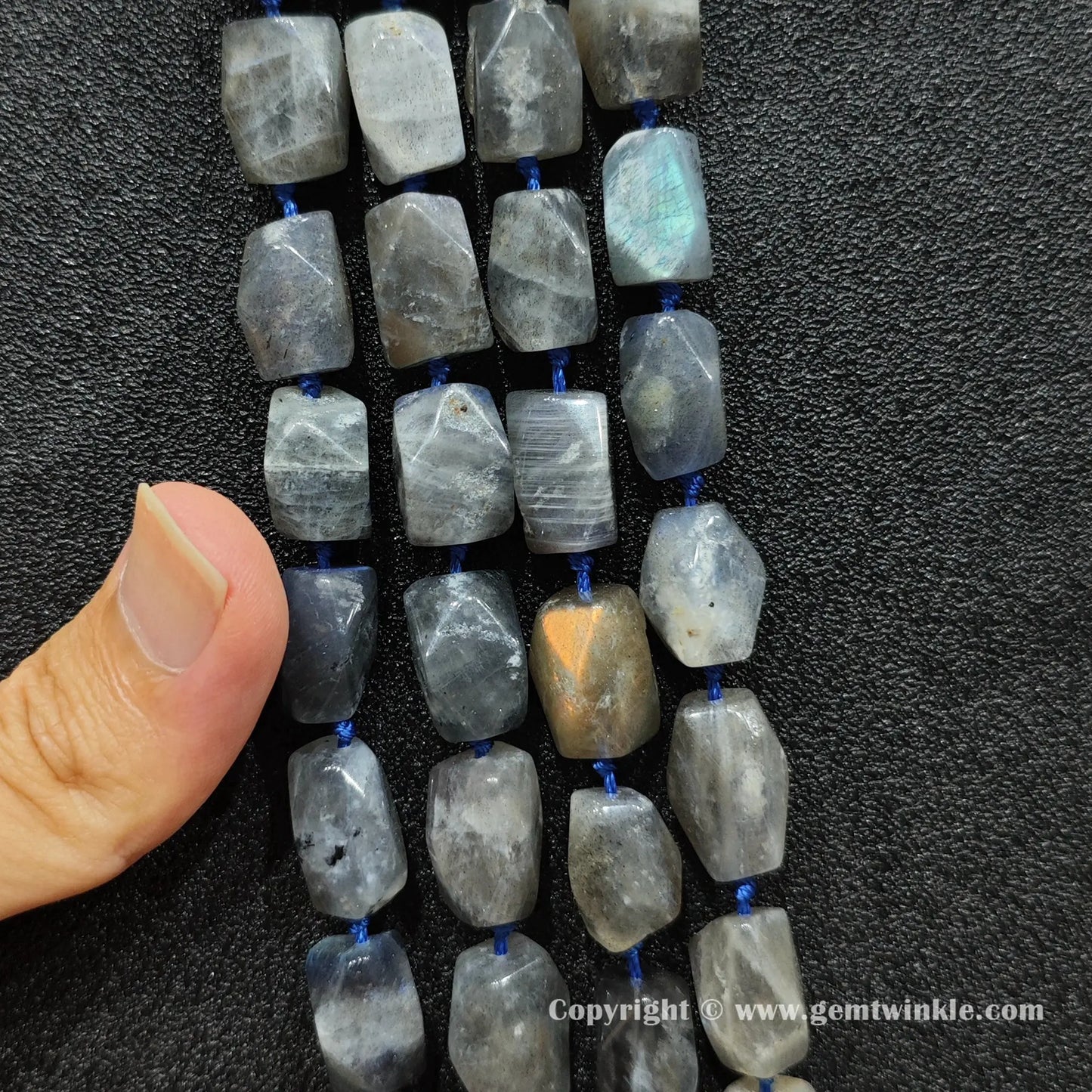 hand holding raw style chunky grey moonstone faceted barrel beads showing scale