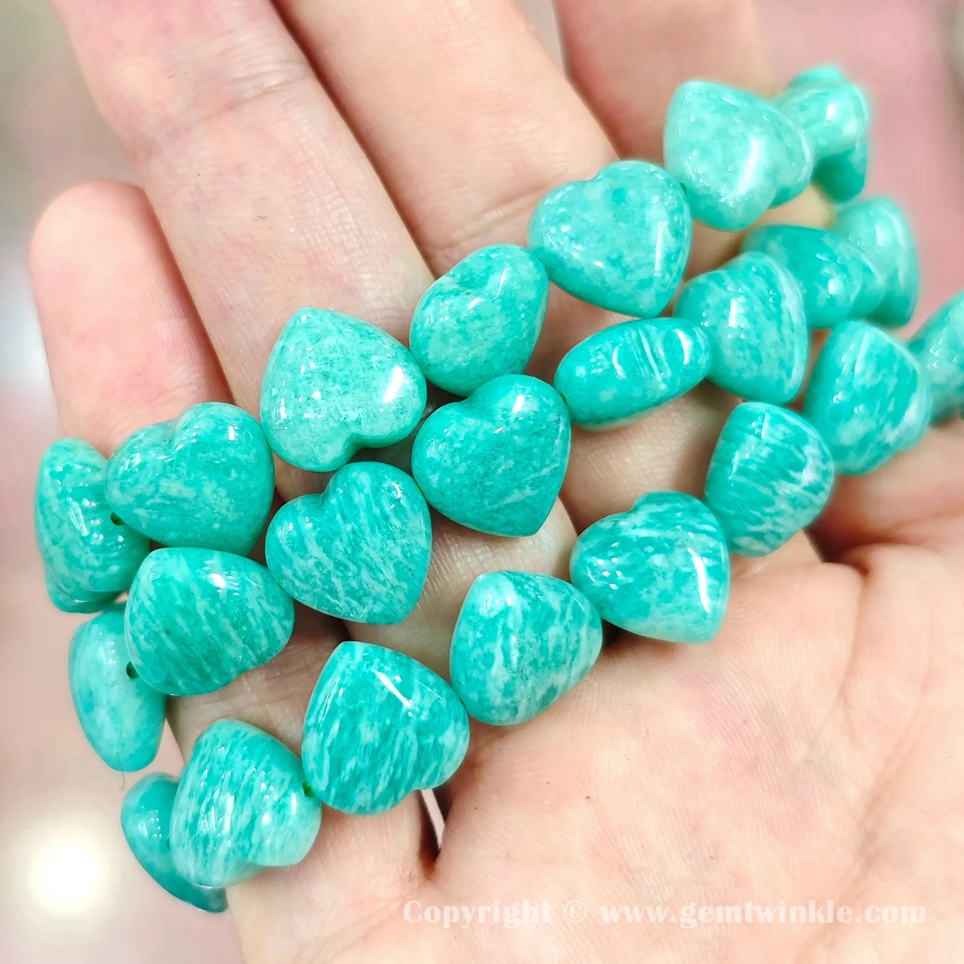 Handheld perspective displaying carved amazonite heart bead strands on hand