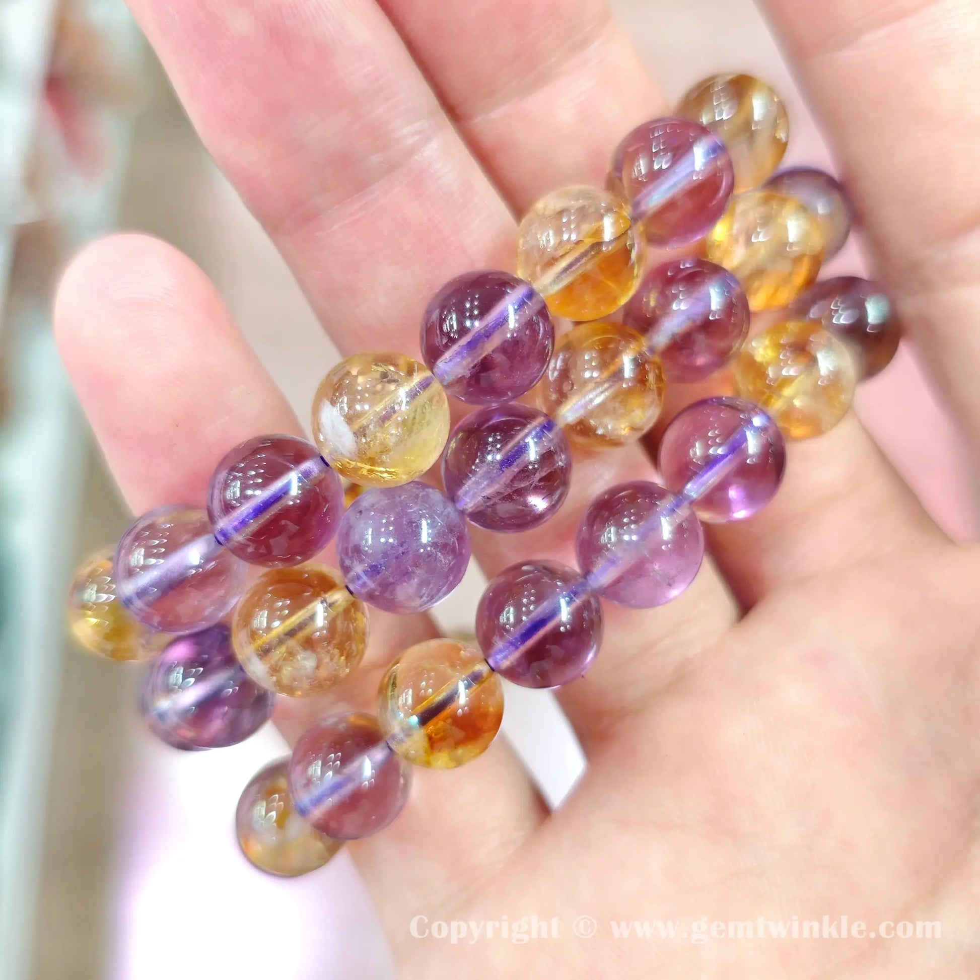 Handheld perspective showing single strand amethyst and citrine bead bracelets on hand