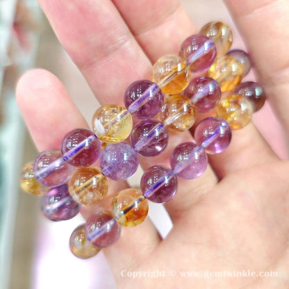 Handheld perspective showing single strand amethyst and citrine bead bracelets on hand