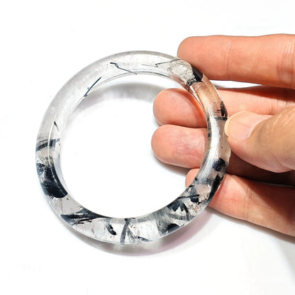 Handheld side view showing transparent quartz crystal with black rutile needle distribution