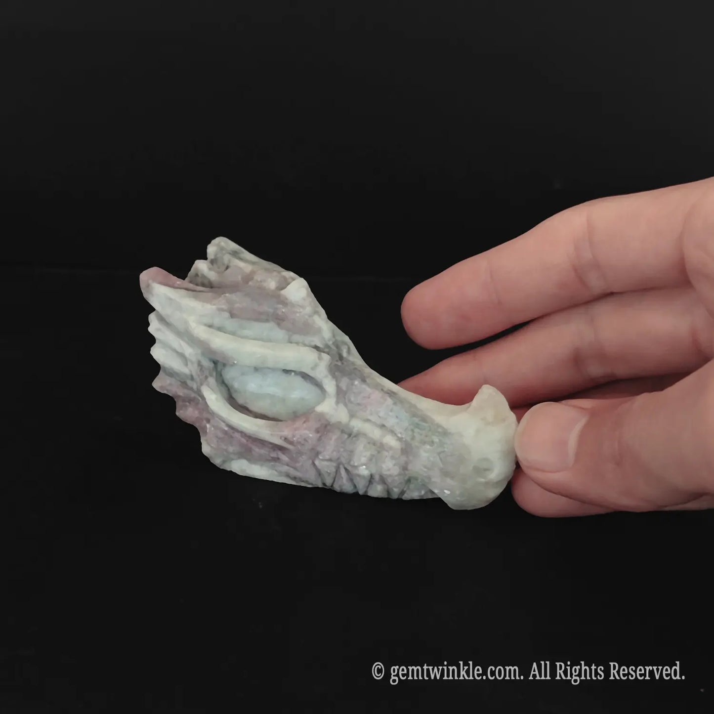 Detailed view of a flower tourmaline dragon head held in hand highlighting artistic carving and stone pattern