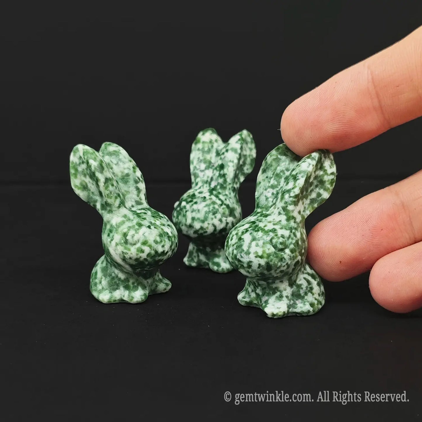 Handheld view of a 4cm green snowflake stone pocket pet rabbit demonstrating real tactile size for crystal shop buyers