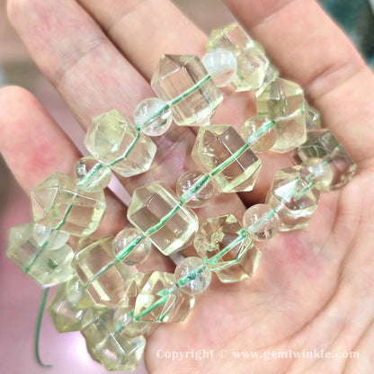 Handheld perspective displaying light yellow lemon quartz double point bead strands on hand