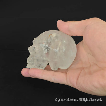 Handheld quartz skull carving showing natural mineral cotton inclusions and organic frosted texture