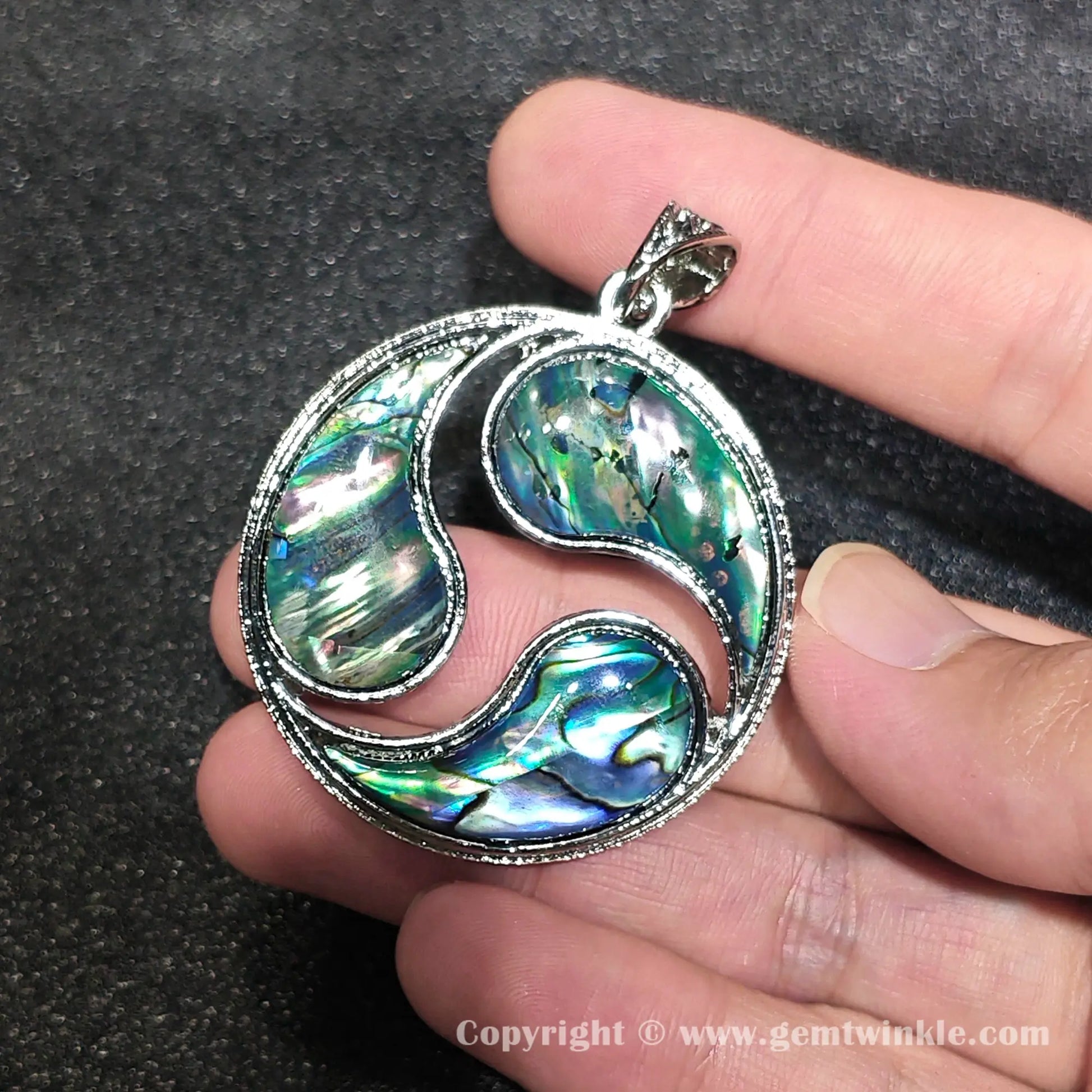 Handheld view showing multi piece abalone shell mosaic shine and 40mm alloy circle pendant layout