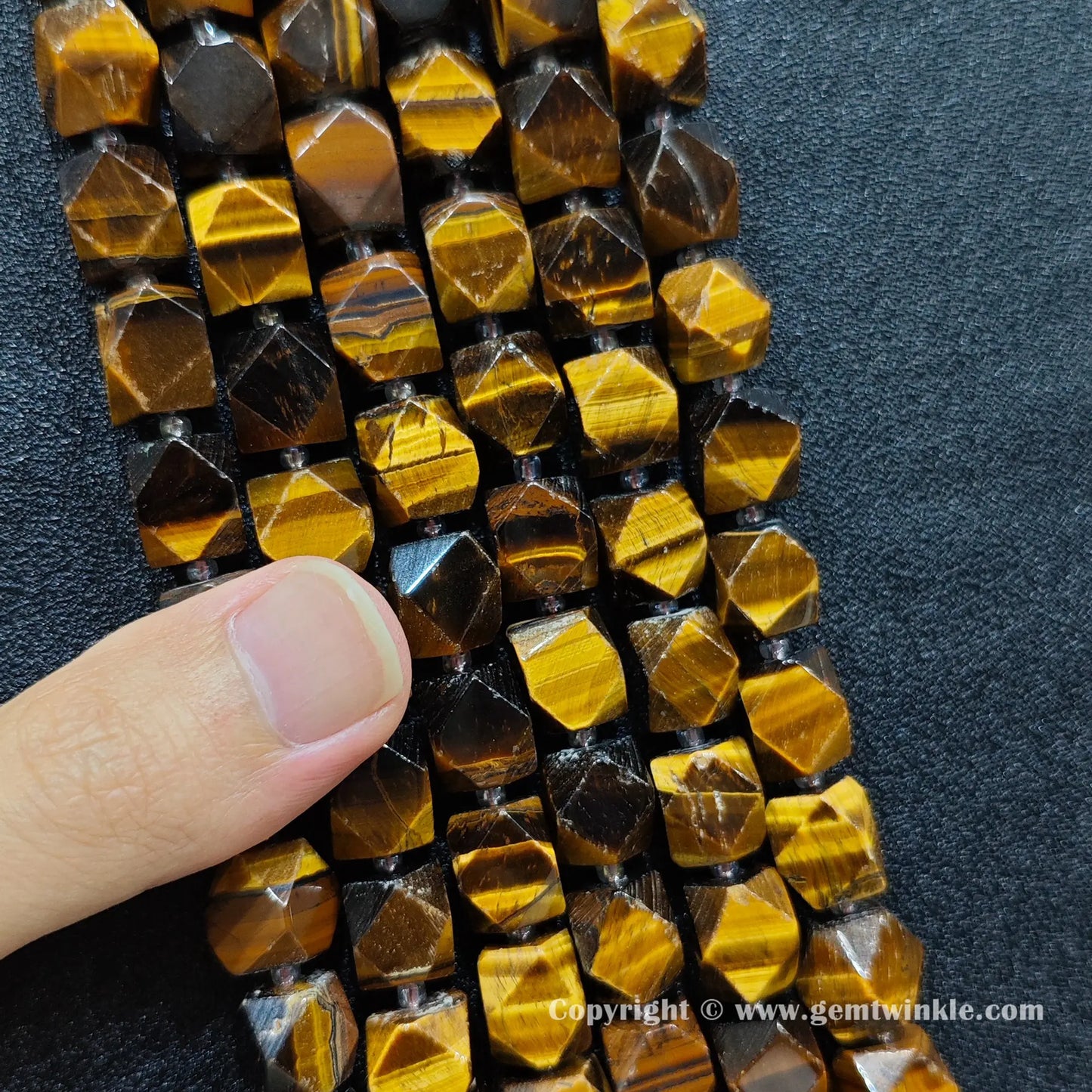 handheld scale view of 12mm faceted yellow tiger eye beads