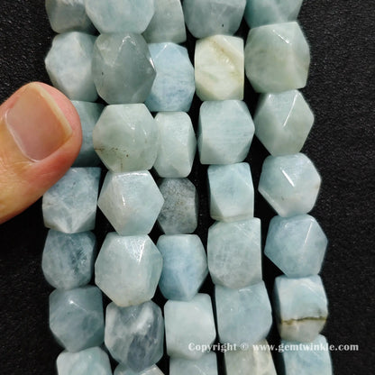 handheld scale view of 13mm faceted aquamarine barrel beads