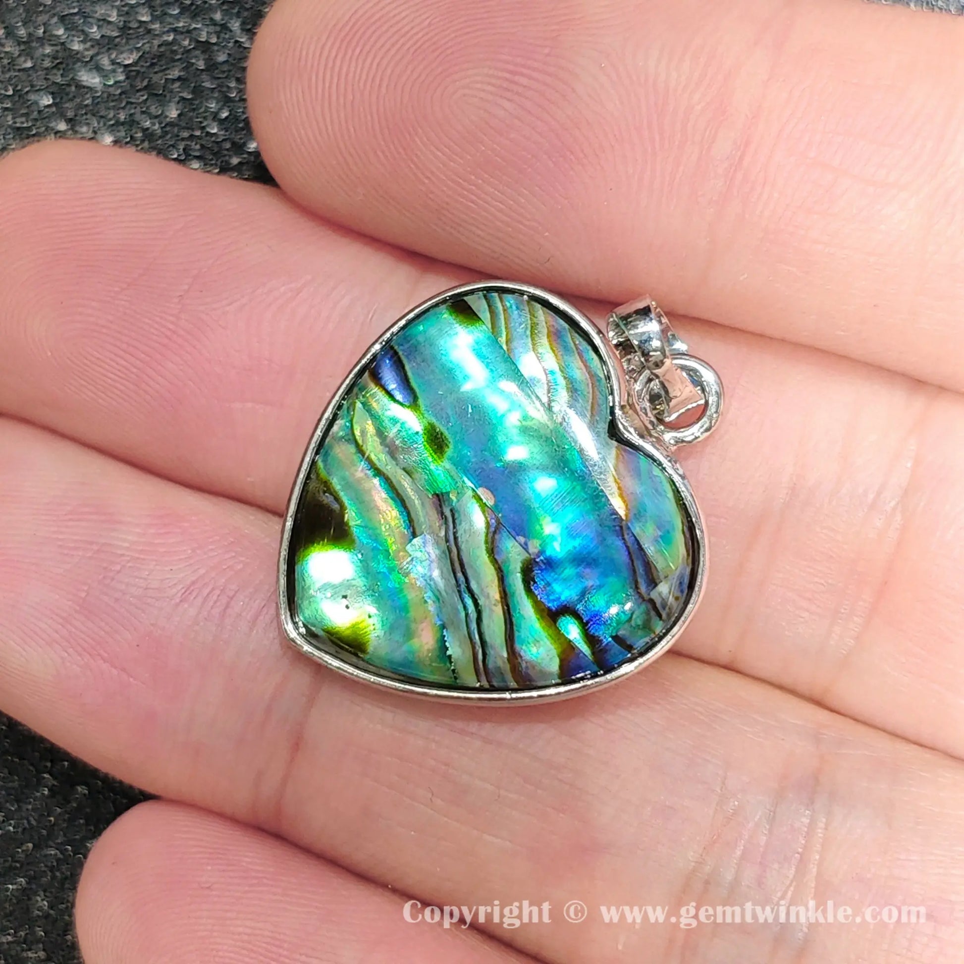 Close up handheld view showing silver top bail and colorful heart mosaic shell reflections