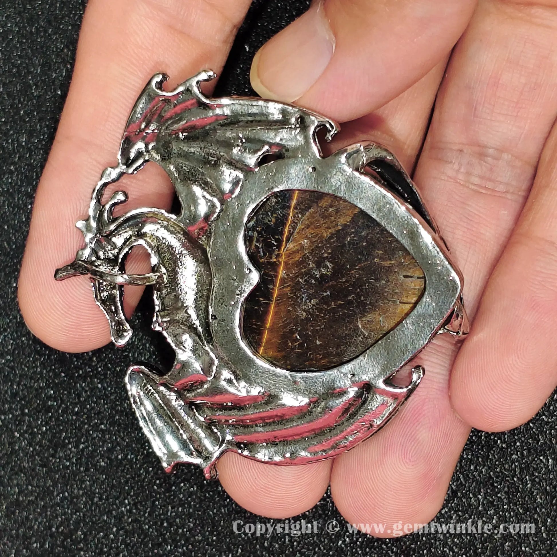 Back view of metallic alloy dragon frame enclosing heart-shaped natural tiger eye stone
