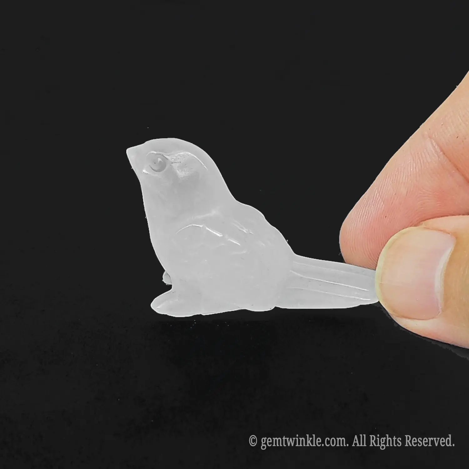 Side profile view of a heavily included clear quartz miniature songbird figurine displaying dense white cloudy phantoms and natural cotton-like internal structures