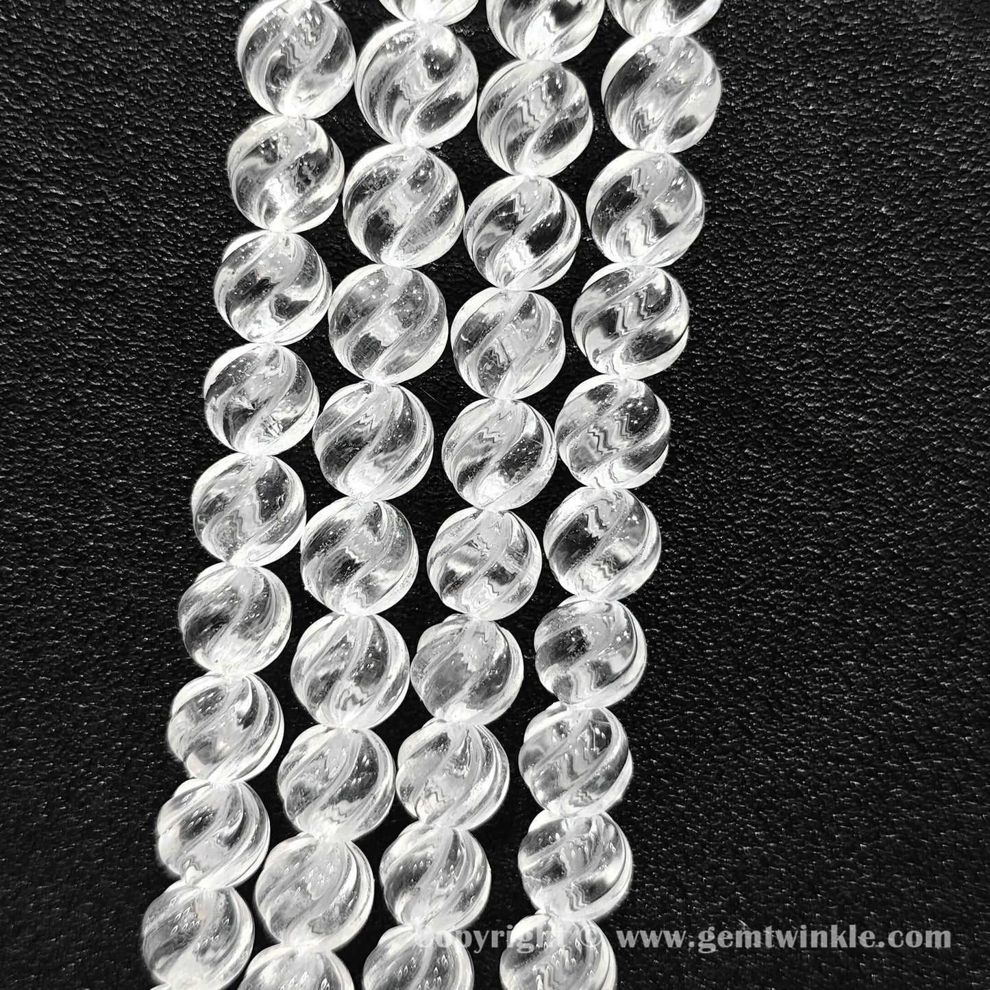 Vertical layout of helical grooved clear quartz beads highlighting carved texture