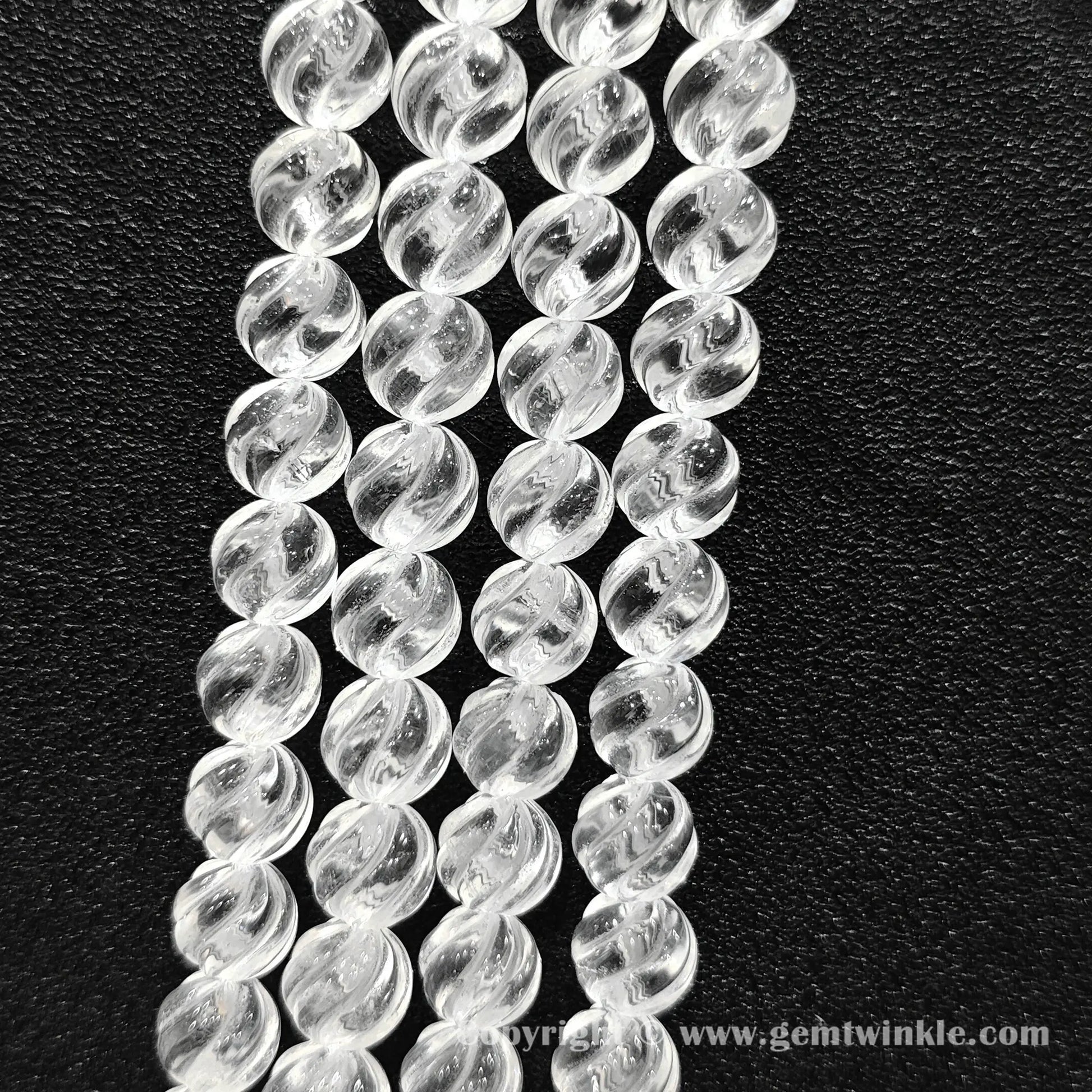 Vertical layout of helical grooved clear quartz beads highlighting carved texture