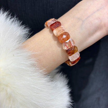 Close-up of a red hematoid fire quartz bracelet worn on a wrist, highlighting the natural stone patterns.